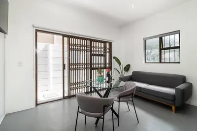 a living room with a couch and a table and chairs at 1Bed Flat, Braai, AC, Walking Distance from Blouberg Beachfront in Cape Town
