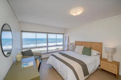 a bedroom with a bed and a view of the ocean at 2 Bedroom Apartment - Blouberg Beachfront in Cape Town