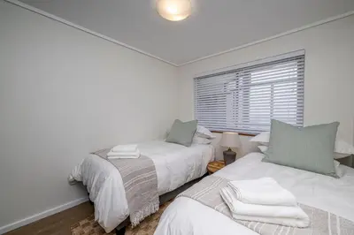 two beds in a white room with a window at 2 Bedroom Apartment - Blouberg Beachfront in Cape Town