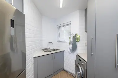 a kitchen with a sink and a washing machine at 2 Bedroom Apartment - Blouberg Beachfront in Cape Town