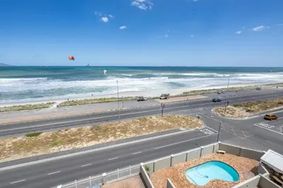 a view of a road and the beach from a building at 2 Bedroom Apartment - Blouberg Beachfront in Cape Town
