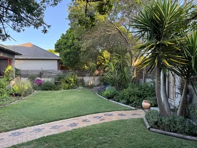 a garden with a lawn and palm trees at Cosy Home with an Ocean Breath! in Cape Town