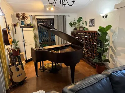 a piano in a living room with a guitar at Cosy Home with an Ocean Breath! in Cape Town