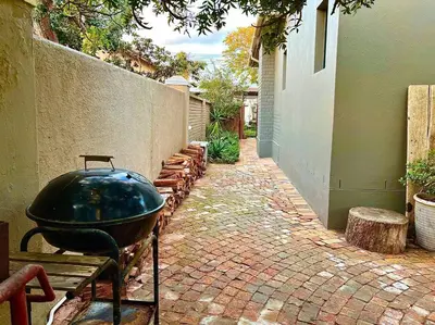 a large grill on a brick walkway next to a building at Cosy Home with an Ocean Breath! in Cape Town