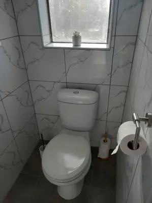 a bathroom with a white toilet and a window at Entire Spacious Guest suite in Cape Town in Cape Town