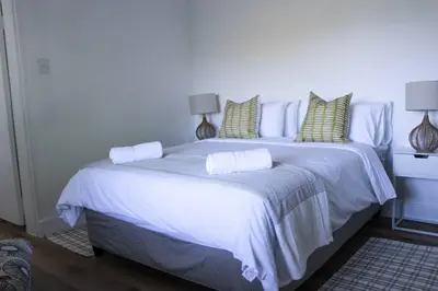 a white bed with pillows on it in a bedroom at Luxury Poolside Villa Irene in Cape Town