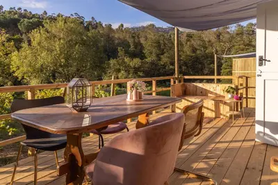 a wooden deck with a wooden table and chairs at The Huts - Glamping at Caledon Grace in Caledon