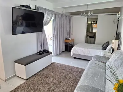 a bedroom with a bed and a flat screen tv at Cosy Cottage Cape Town in Cape Town