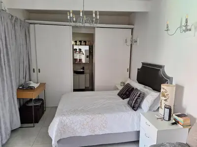 a bedroom with a bed and a desk and a chandelier at Cosy Cottage Cape Town in Cape Town