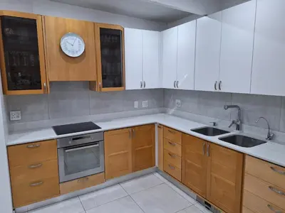 a kitchen with wooden cabinets and a clock on the wall at Cosy Cottage Cape Town in Cape Town