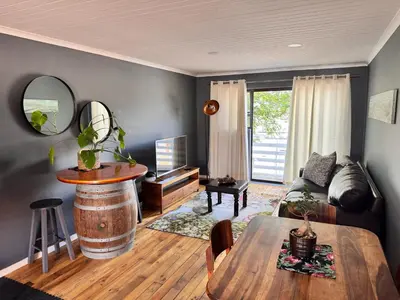 a living room with a table and a couch and a barrel at Ocean Breath Apartment in Strand