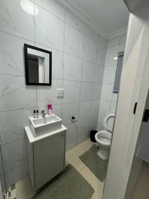 a white bathroom with a sink and a toilet at Canary Guest house in Cape Town