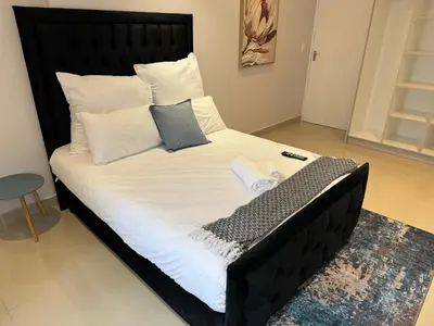 a large black bed with white sheets and pillows at Canary Guest house in Cape Town
