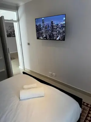 a bedroom with a bed with a tv on the wall at Canary Guest house in Cape Town