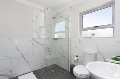 a white bathroom with a toilet and a sink at Elegant apartment near beach in Cape Town