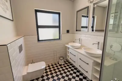 a white bathroom with two sinks and a toilet at Waveren's Nest in Cape Town