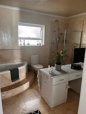 a bathroom with a tub and a toilet and a sink at Voëlklip Holiday Home in Hermanus