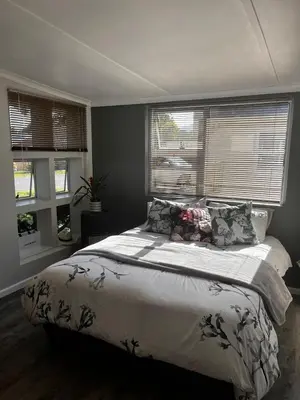 a bedroom with a large bed and two windows at Voëlklip Holiday Home in Hermanus