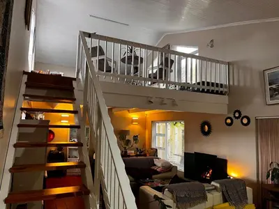 a living room with a spiral staircase in a house at Voëlklip Holiday Home in Hermanus