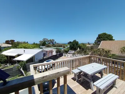 a deck with a table and benches on a balcony at 45 on Luke in Hermanus