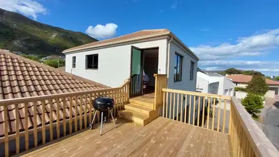 a house with a wooden deck with a staircase at 45 on Luke in Hermanus