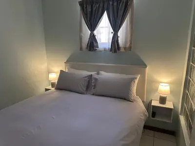 a bedroom with a white bed and a window at Casa on Alamein in Cape Town