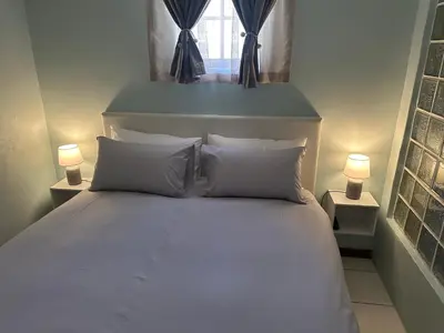 a white bed with two pillows and a window at Casa on Alamein in Cape Town