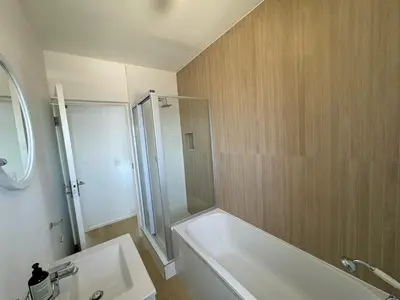 a bathroom with a white tub and a sink at BEACHFRONT Breeze in Cape Town