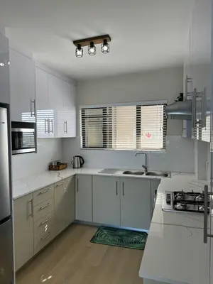a kitchen with white cabinets and stainless steel appliances at BEACHFRONT Breeze in Cape Town