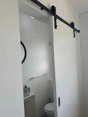 a bathroom with a white toilet and a white wall at BEACHFRONT Breeze in Cape Town