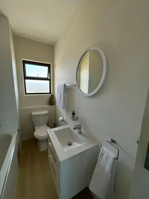 a bathroom with a sink and a toilet and a mirror at BEACHFRONT Breeze in Cape Town