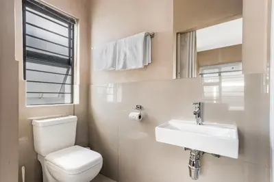 a white bathroom with a toilet and a sink at The Greenfields Suite in Cape Town