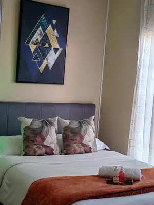a bedroom with a bed with a painting on the wall at The Greenfields Suite in Cape Town