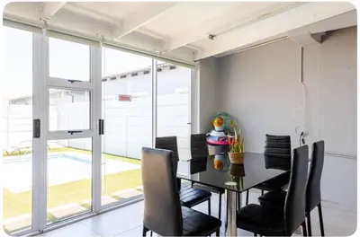 a dining room with a table and black chairs at JDBA Homes of Luxury in Cape Town