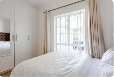 a bedroom with a white bed and a window at JDBA Homes of Luxury in Cape Town