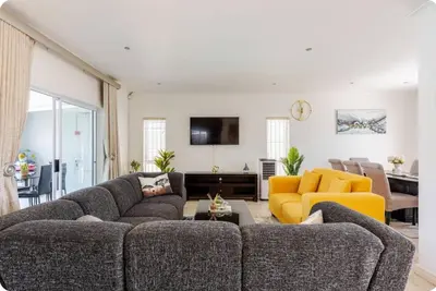 a living room with two couches and a yellow chair at JDBA Homes of Luxury in Cape Town