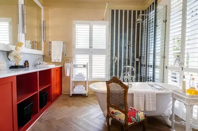 a bathroom with a tub and a sink and a chair at Birkenhead House in Hermanus