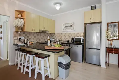 a kitchen with a large island with bar stools at Unwind at Coral 2BR Bloubergstrand Beach Apt Walk to Beach in Bloubergstrand