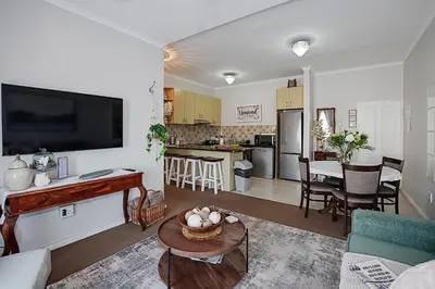a living room with a couch and a table and a kitchen at Unwind at Coral 2BR Bloubergstrand Beach Apt Walk to Beach in Bloubergstrand