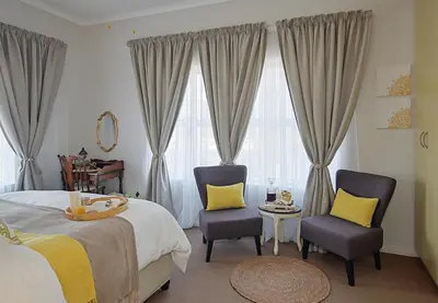 a bedroom with two chairs and a bed and windows at Unwind at Coral 2BR Bloubergstrand Beach Apt Walk to Beach in Bloubergstrand