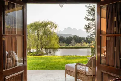 a door leading to a patio with a view of a lake at La Residence in Franschhoek