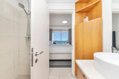 a bathroom with a shower and a bathroom with a bed at Horizon Bay 202 Beachfront APT, Bloubergstrand in Cape Town