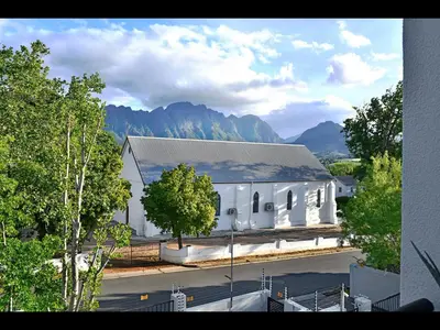 a large white building with mountains in the background at Sorbonne 6 in Franschhoek