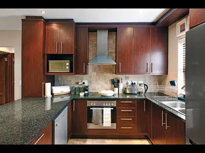 a kitchen with wooden cabinets and a stove top oven at Sorbonne 6 in Franschhoek
