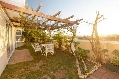 a patio with a table and chairs under a pergola at 3 Bedroom part house in the scenic Durbanville wine lands area, holiday facility in Cape Town