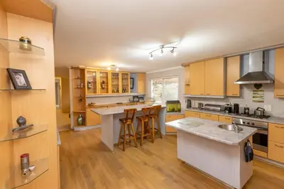 a kitchen with wooden cabinets and a kitchen island with bar stools at 3 Bedroom part house in the scenic Durbanville wine lands area, holiday facility in Cape Town