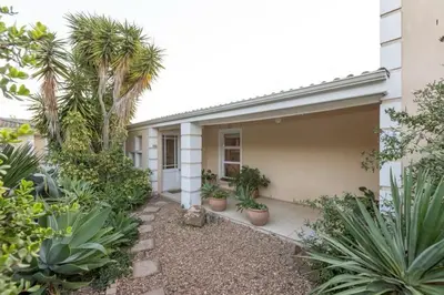 a house with palm trees and plants in front of it at 3 Bedroom part house in the scenic Durbanville wine lands area, holiday facility in Cape Town