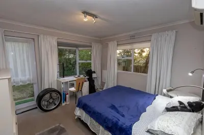 a bedroom with a bed and a desk and windows at 3 Bedroom part house in the scenic Durbanville wine lands area, holiday facility in Cape Town