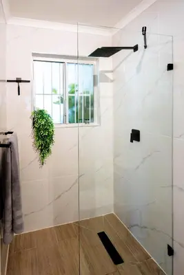 a glass shower in a bathroom with a window at Von Chambers Blouberg in Cape Town