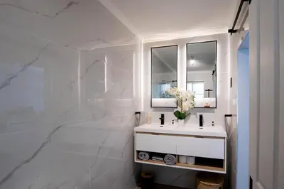 a white bathroom with a sink and a mirror at Von Chambers Blouberg in Cape Town